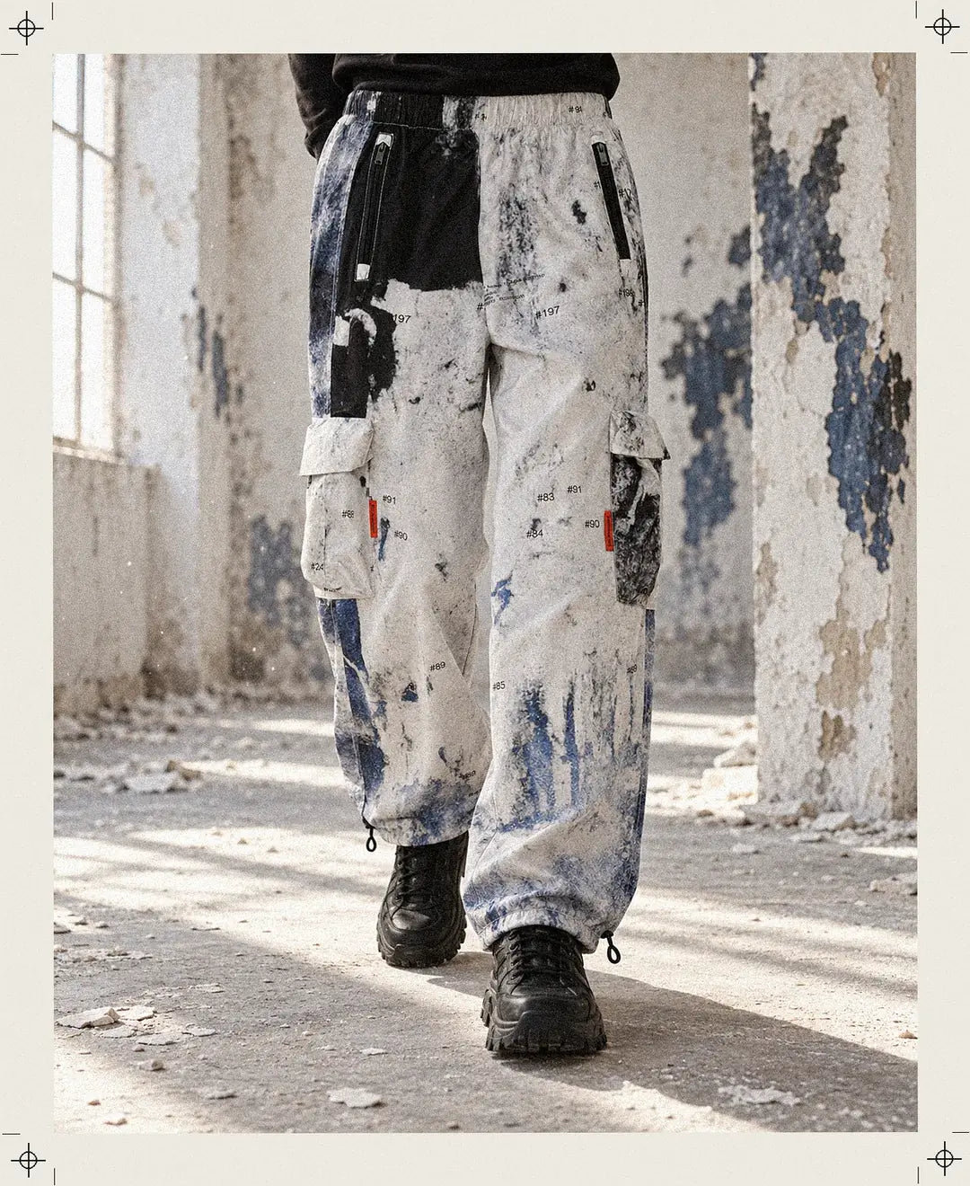 Una persona inventata, inquadrata dalla vita in giù, cammina con il Rugged Cargo in una sala di intonaco bianco grattato fino agli strati blu e neri.