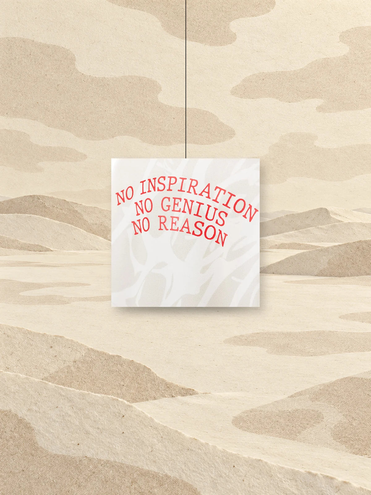 Um quadrado recortado do estampado do hoodie No Genius, com a inscrição vermelha NO INSPIRATION NO GENIUS NO REASON, pendurado num fio sobre um campo de papel marfim.