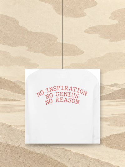 Kus potisku na zádech bílé mikiny s kapucí No Inspiration, s červeným nápisem NO INSPIRATION NO GENIUS NO REASON, zavěšený na niti nad polem ze slonovinového papíru.