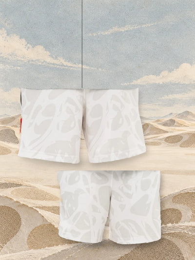 البرمودا العاجية Strand Ivory من الخلف، معلّقة بخيط، ومن الأمام، فوق كثبان من الورق بلون الرمل.