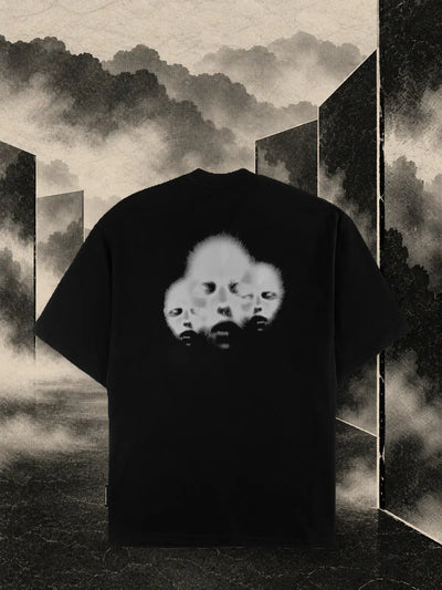 Czarny T-shirt Triodrome wśród paneli z ciemnego papieru i mgły w kolorze piasku.