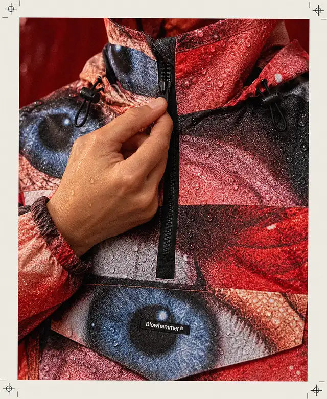 Una mano inventata tira su la zip nera del Love Act Anorak, con l'occhio stampato sulla patta.
